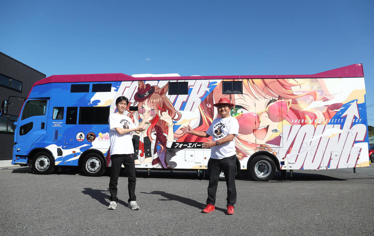 完成したウマ娘のフォーエバーヤンがグラッピングされた馬運車をアピールする坂井瑠星騎手（左）と矢作芳人調教師（撮影・白石智彦）