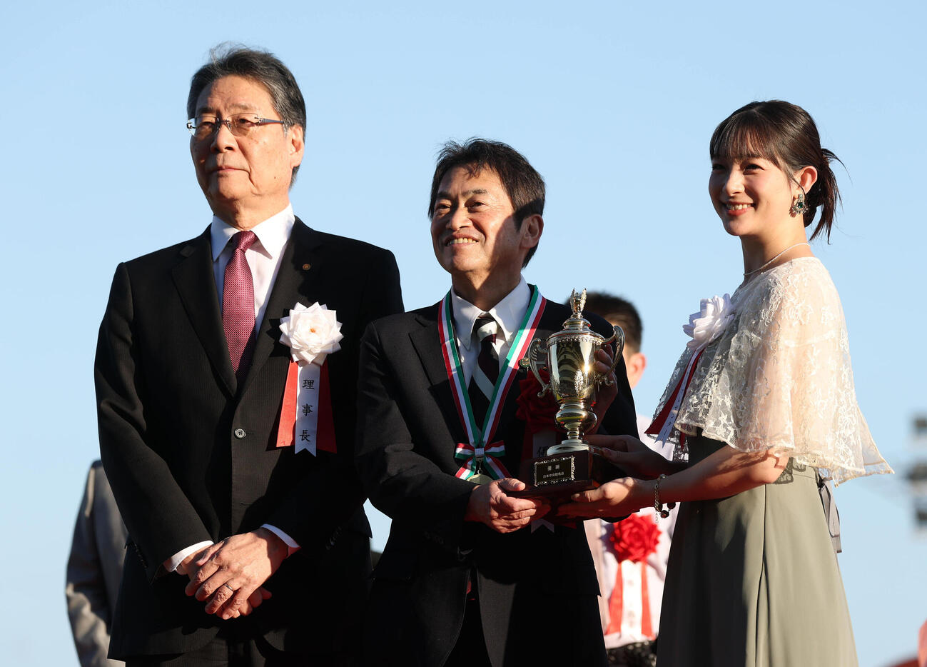 記念写真に納まる、左から吉田正義JRA理事長、エムズレーシング杉野公彦オーナー、プレゼンター足立梨花