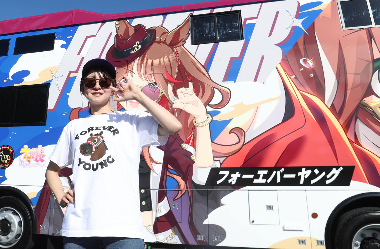 ウマ娘のフォーエバーヤンがグラッピングされた馬運車を背に同じポーズする古川奈穂騎手（2026年10月15日撮影）
