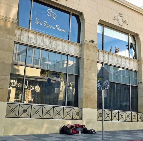 ハリウッドの中心地にあるホテルの横で眠るホームレス