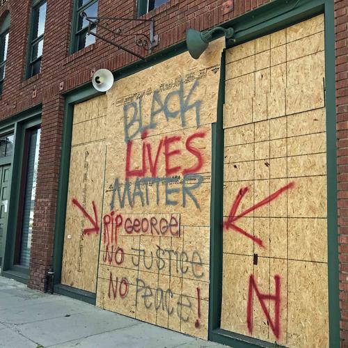 防護板にBlack Lives Matterとメッセージを掲げる衣料品店。正義がない限り、平和もないと書かれています