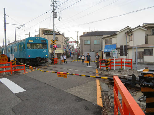 〈10〉商店街前の踏切を行く103系