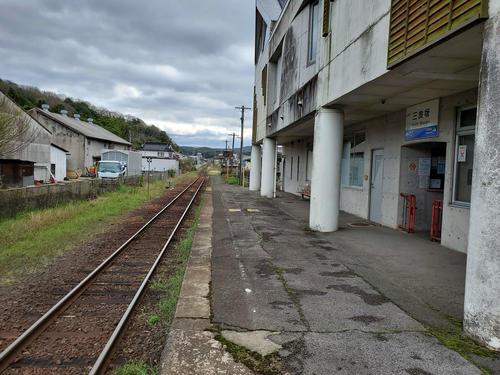 〈11〉三良坂の駅名標とホーム。かつては2面ホームがあったが、今はフェンスの向こうに跡が残るのみ