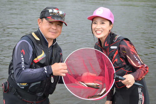 獲物のアユを手に笑顔を見せるオカマリ（右）とコーチ役の岡崎さん