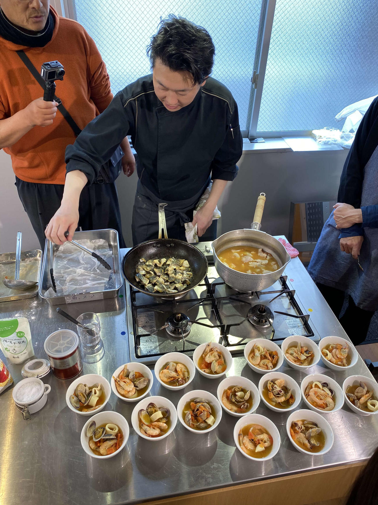 宮田シェフはオニカサゴのブイヤベースとサバのポワレを同時に仕上げていく。その様子を動画撮影するタコボウズ記者（撮影・斉藤真美さん＝料理も）