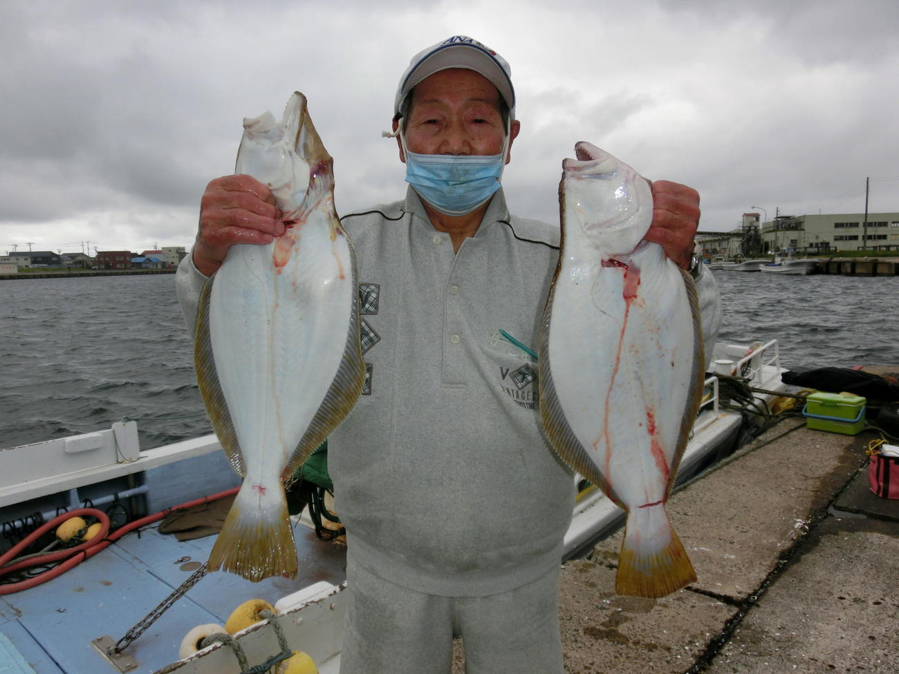 釣り上げたヒラメを掲げる札幌市の本間実さん