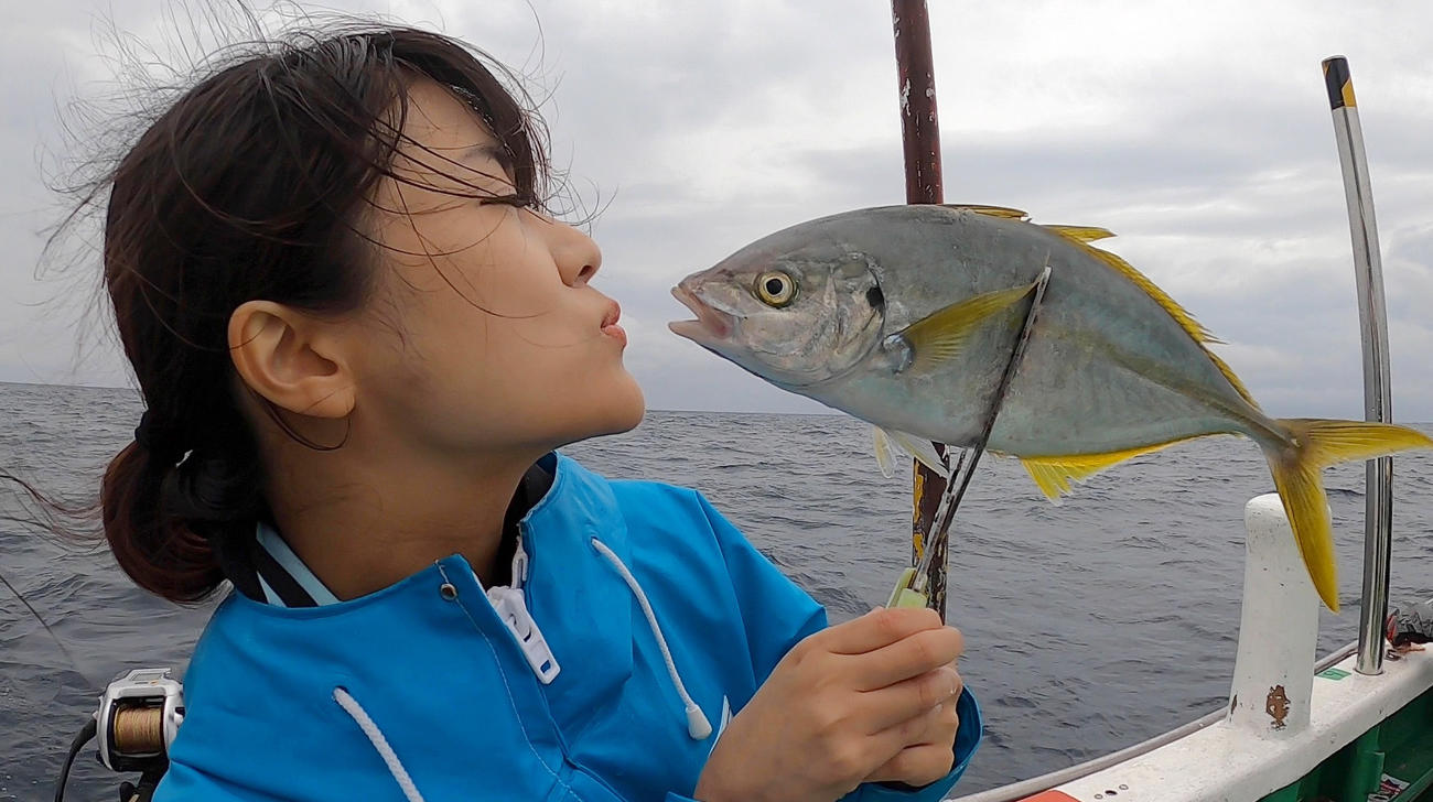 釣りあげたシマアジに唇を寄せる出光仁美