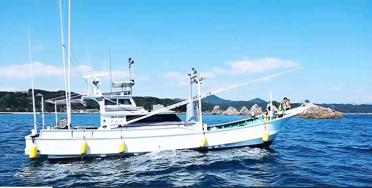 潮風を受けながらのんびり湾内クルーズを楽しむ観光客