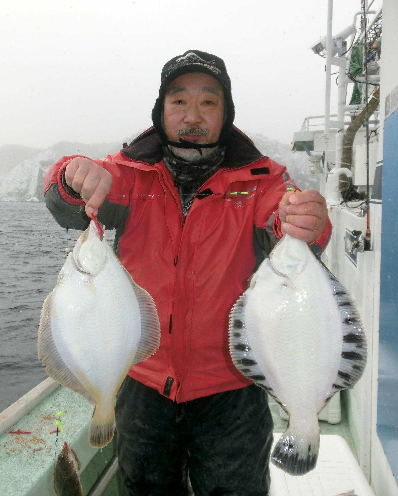 積丹婦美沖で釣り上げたマガレイ、クロガシラを手にする札幌市の後藤浩一さん