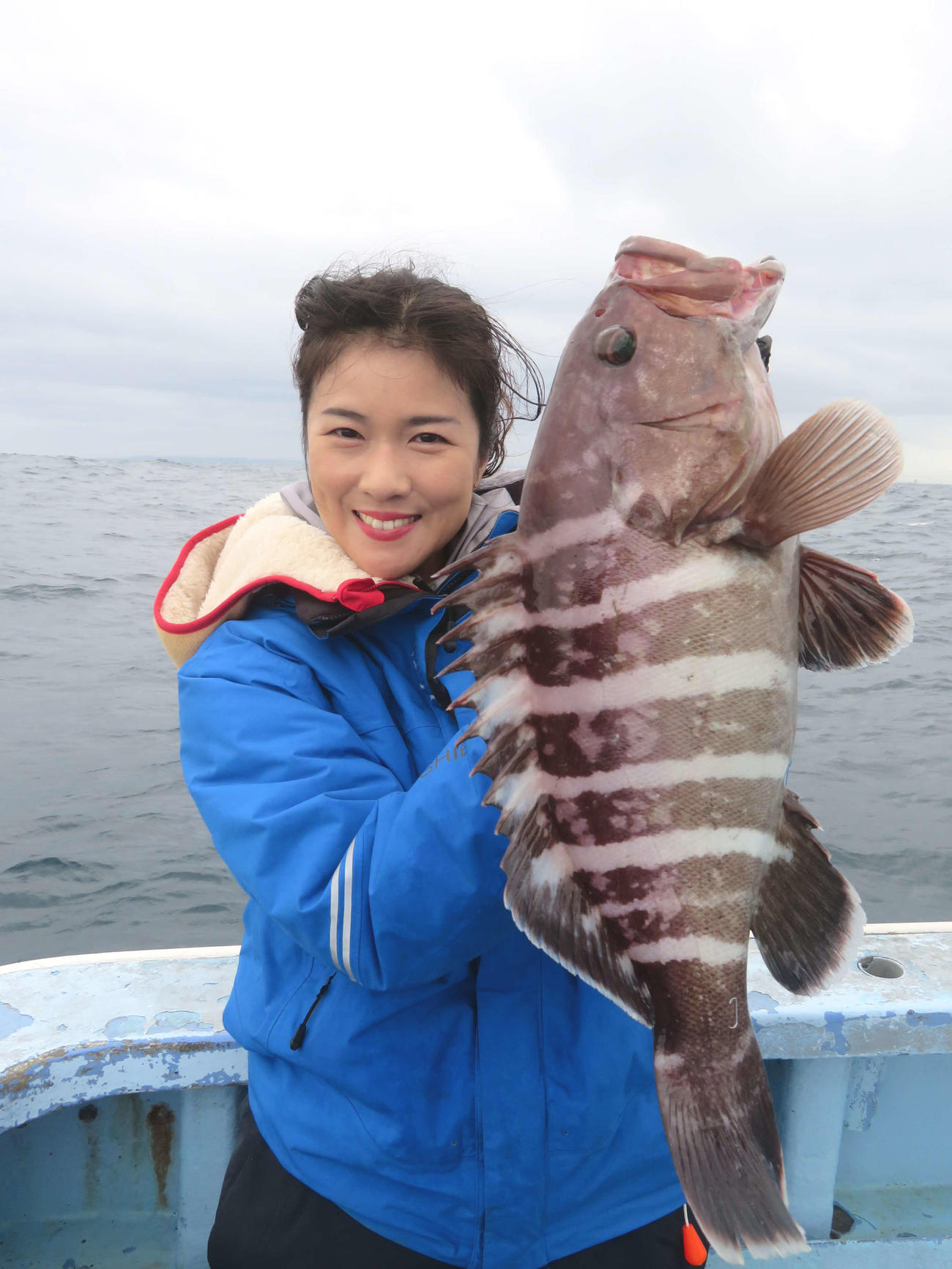 人生初のアタリなしボウズ。記者が釣り上げたマハタを掲げニッコリだが、心中穏やかではかった出光仁美（撮影・川田和博）