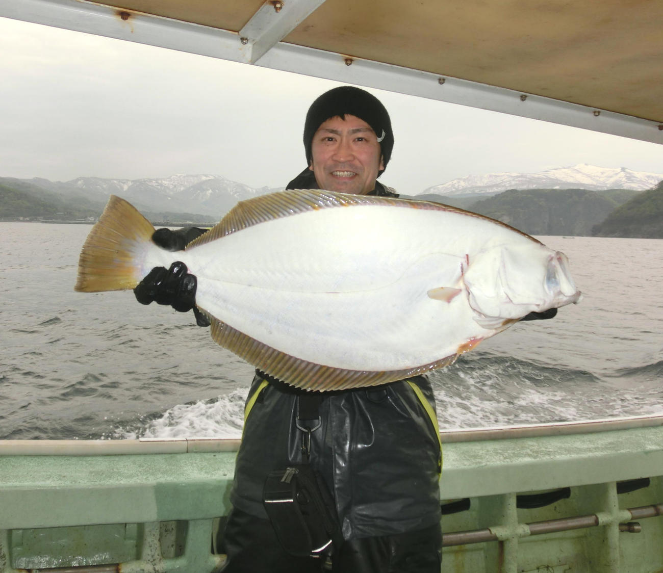 美国沖で61センチの大物ヒラメを釣り、笑顔を見せる佐々木さん