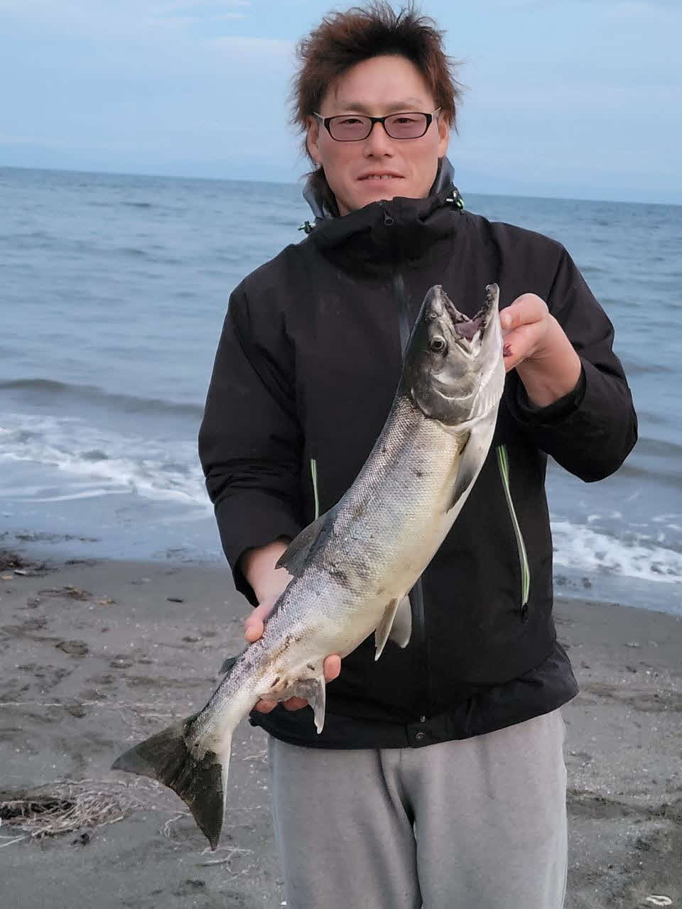 釣り上げたばかりのサケを手に笑顔の西将騎手
