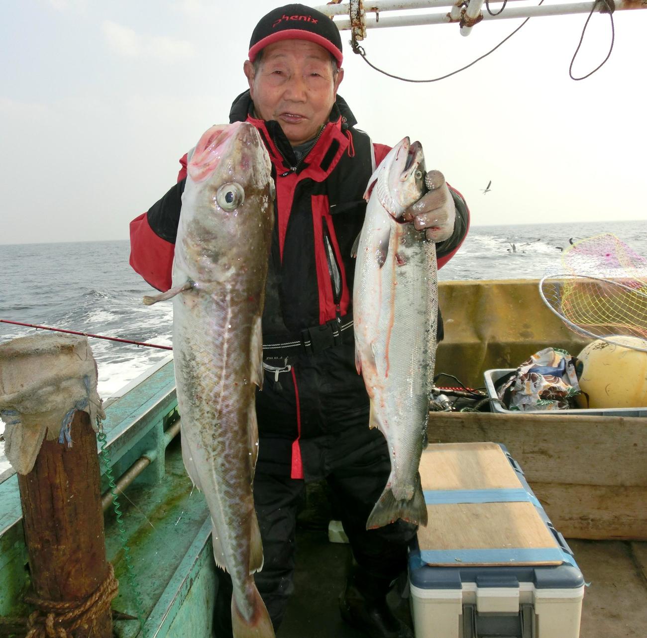 漁運丸でマダラとサクラマスを手にする札幌市の本間実さん