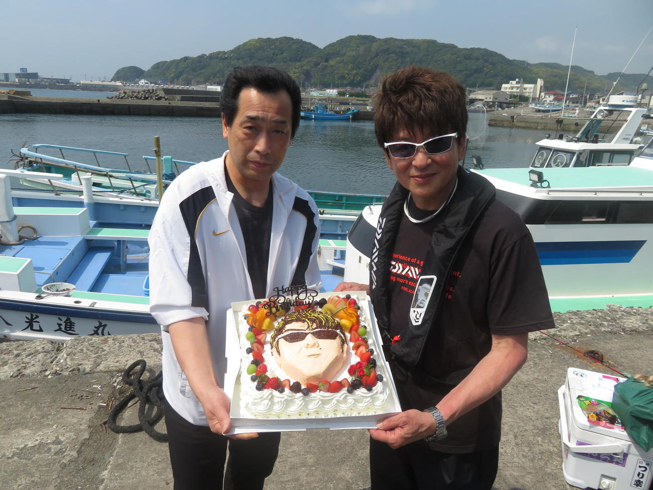 地元洋菓子店「カスタード」の宇渡展雄社長（左）がサプライズで用意したケーキを受け取るアニキ