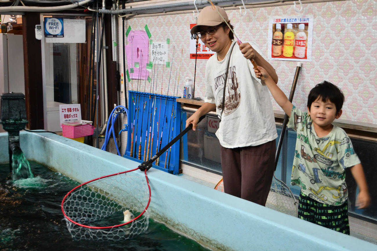 銭湯を改造した釣り堀で釣りを楽しむ親子連れ