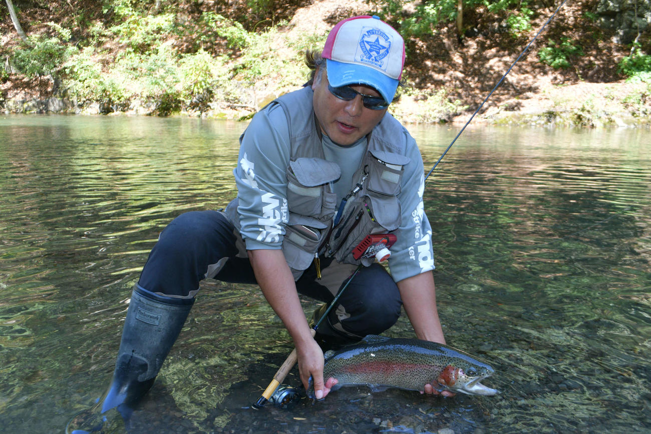 ヤマメ釣りの応用練習という稲村喜久さん（地元漁協の許可を得て魚体に触れています）