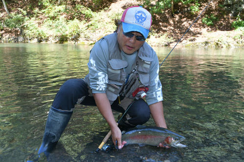 ヤマメ釣りの応用練習という稲村喜久さん（地元漁協の許可を得て魚体に触れています）