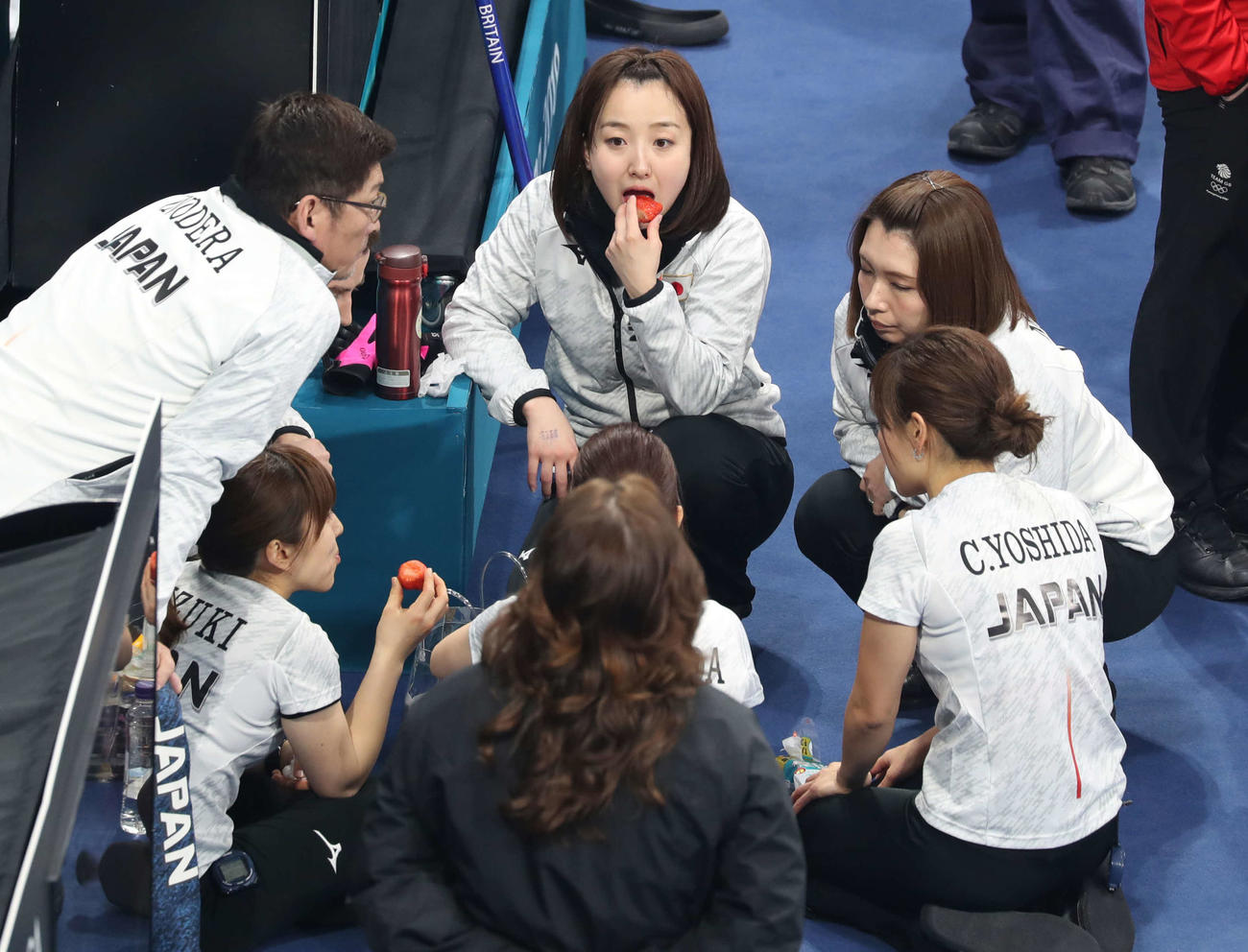 3位決定戦　日本対英国　第5エンドを終え、大きないちごを頬張りながら作戦を練るスキップ藤沢（中央）。右はリザーブ本橋＝2018年2月24日