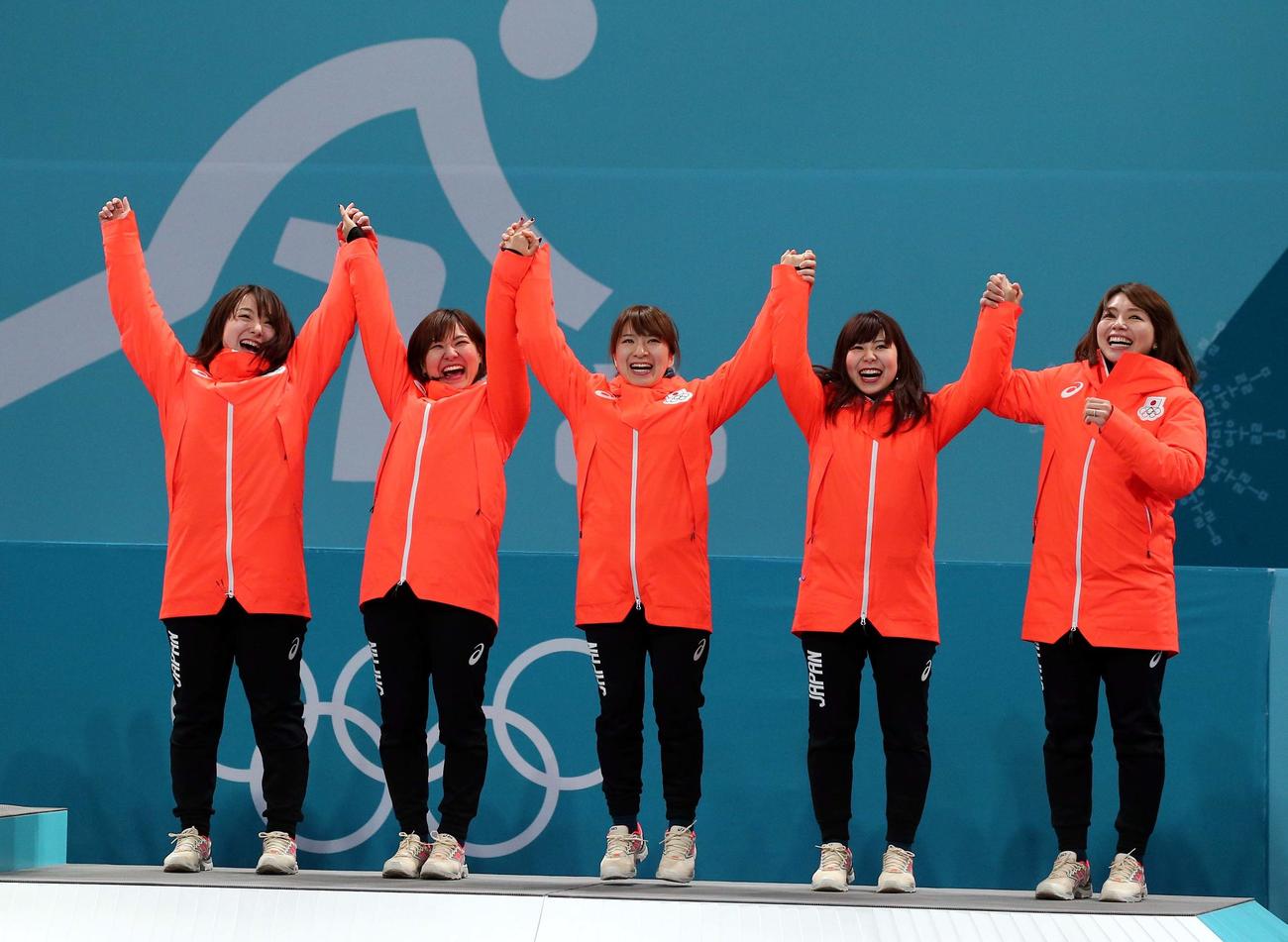 銅メダルを獲得し表彰台で手を上げる左から藤沢、吉田知、鈴木、吉田夕、本橋＝2018年2月23日