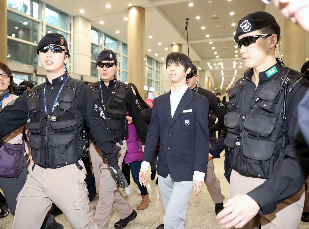 韓国に到着し、セキュリティに守られて空港内を歩く羽生（右から2人目）＝2018年2月11日
