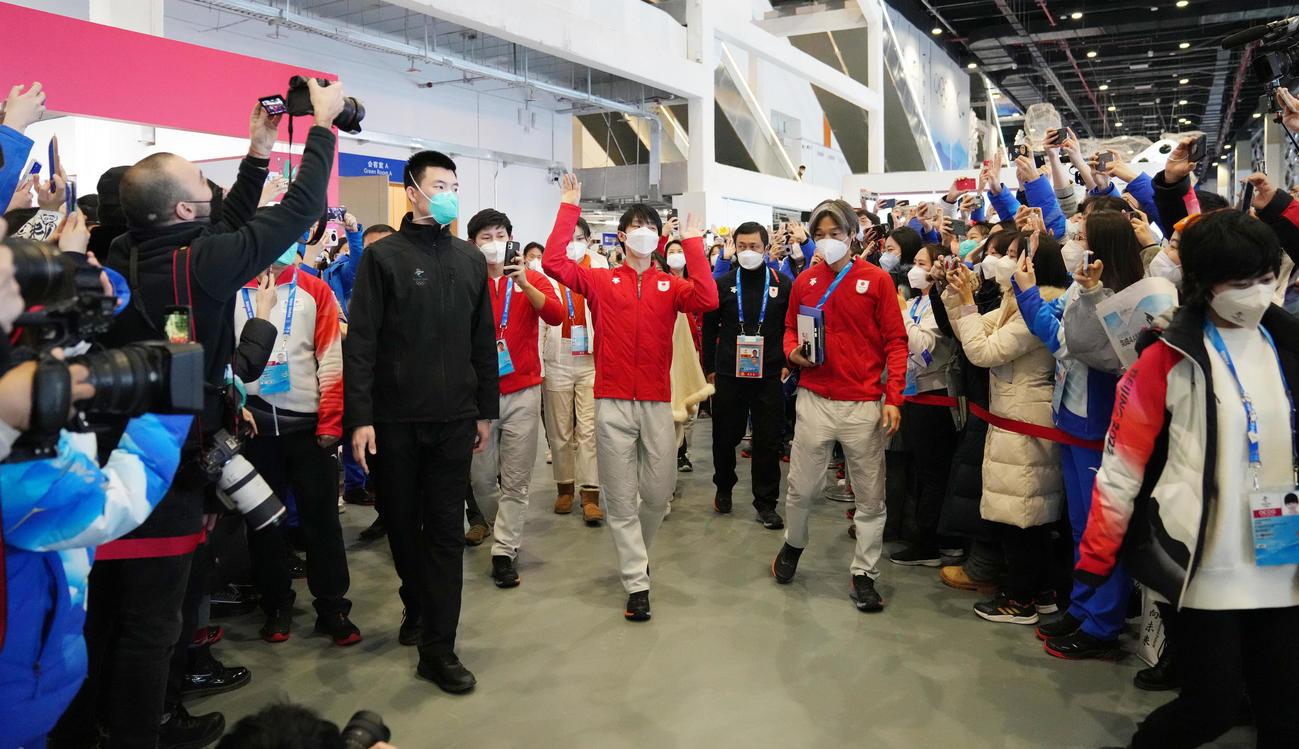 ボランティアと報道陣に囲まれ会見場に向かう羽生（撮影・菅敏）