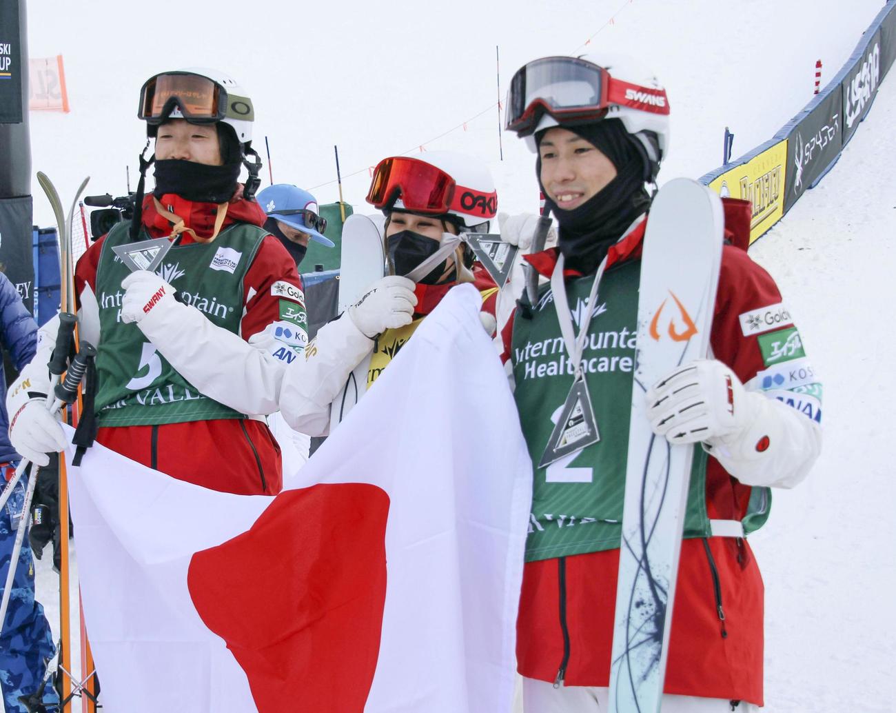日の丸を手に笑顔を見せる男子2位の堀島行真（右）と3位の杉本幸祐（左）。中央は女子2位の川村あんり（共同）