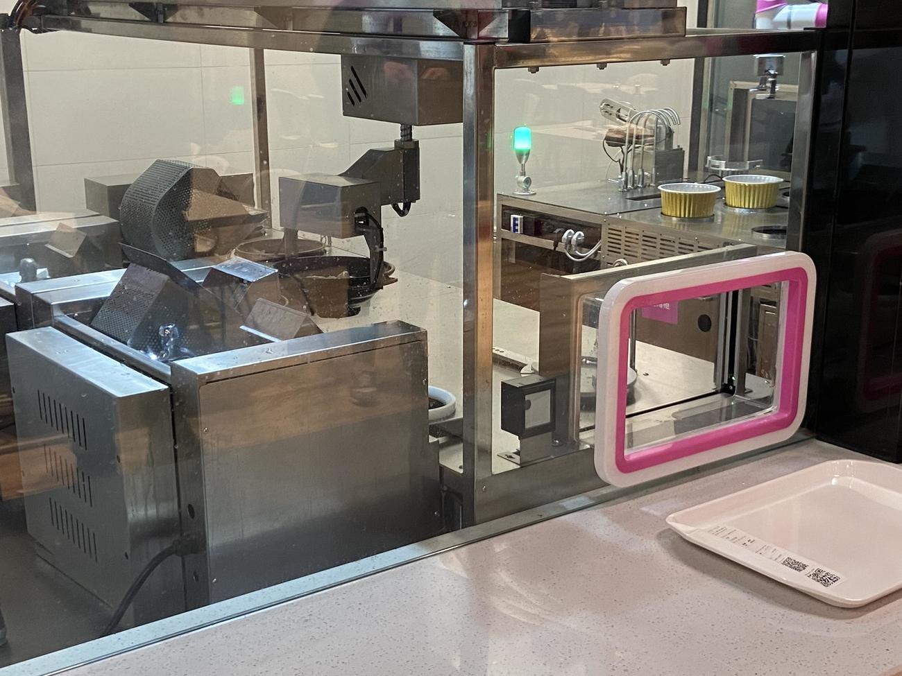 北京五輪のメインメディアセンター内にある食堂で、丼を持ち上げるロボット（撮影・松本航）