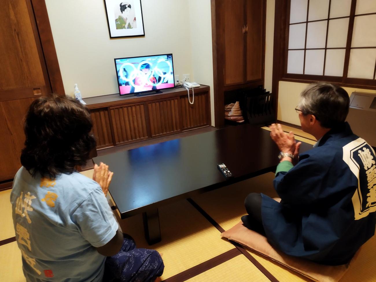 テレビの前で声援を送る峡雲荘の高橋代表と妻孝子さん（峡雲荘提供）