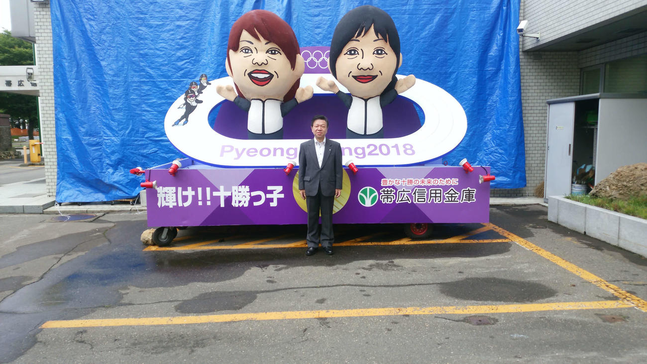 高木菜那、美帆姉妹の山車を背にして写真に納まる帯広信用金庫の高橋理事長（帯広信用金庫提供）