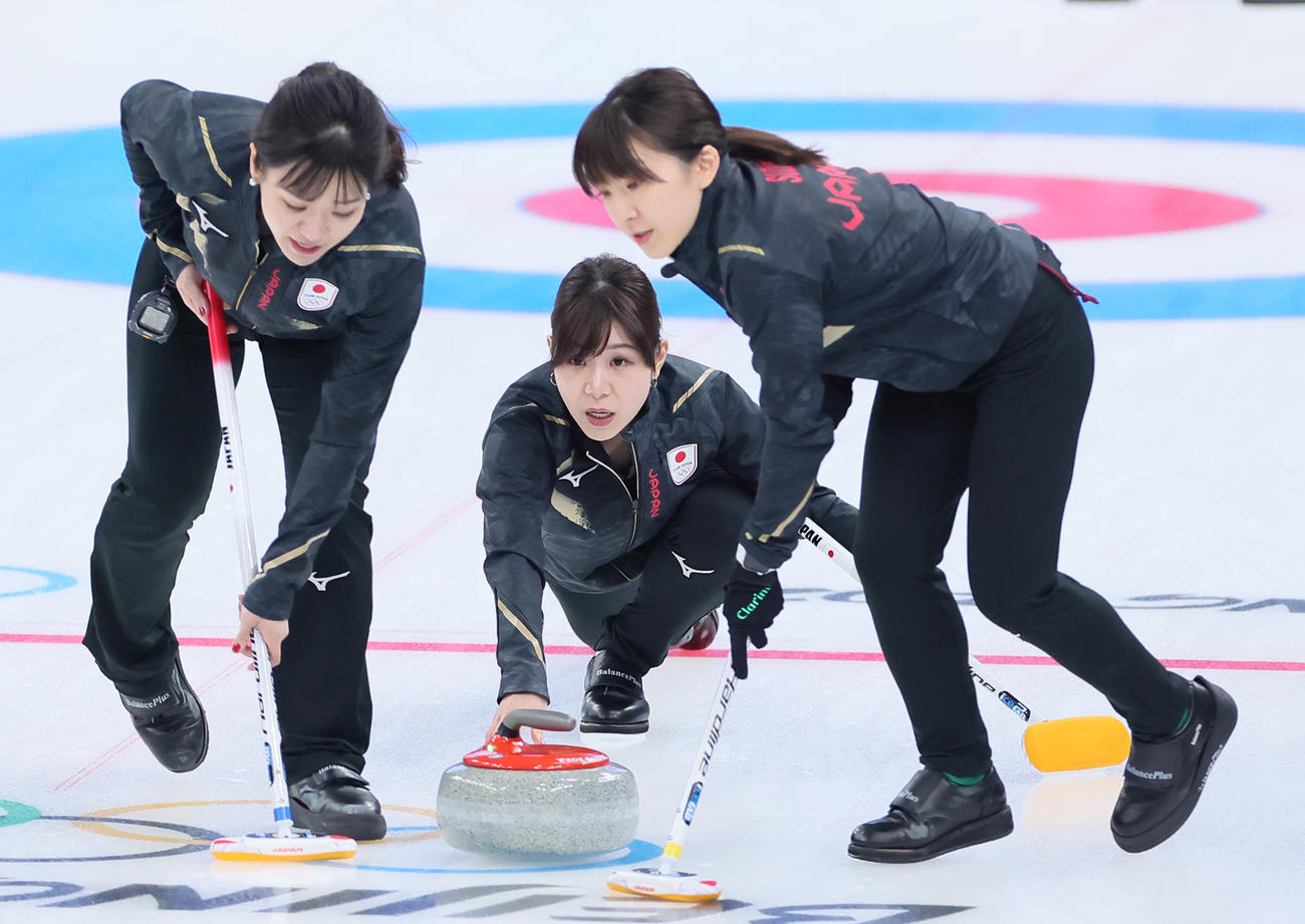 日本対デンマーク　第2エンド、ストーンを投じる吉田夕（中央）。左は吉田知、右は鈴木（撮影・足立雅史）
