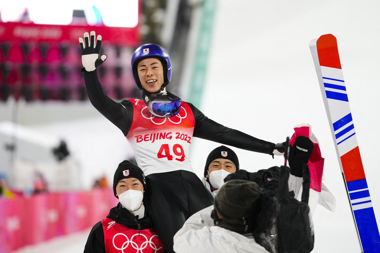 スキージャンプ男子個人ノーマルヒルで金メダルを獲得した小林陵侑はチームメートに抱えられて笑顔を見せる（AP）