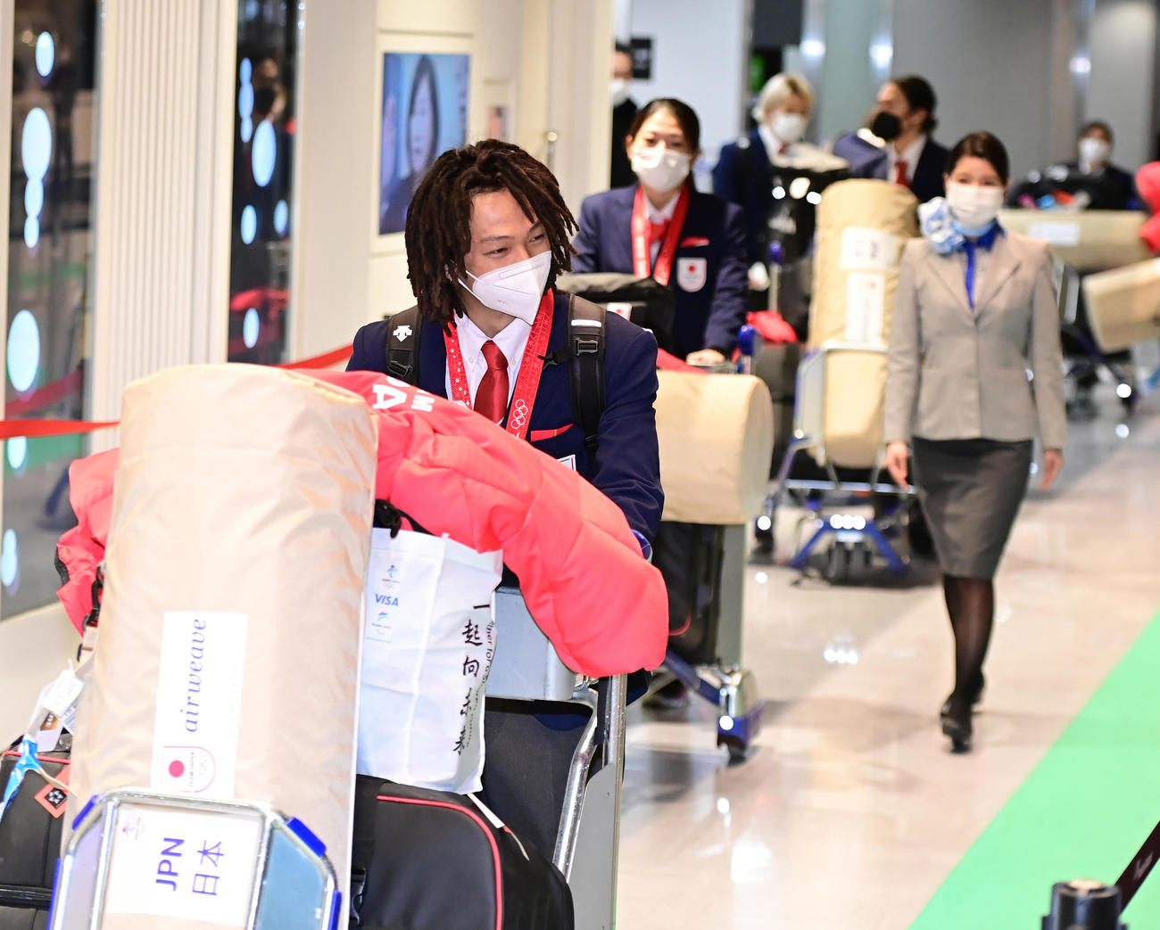 北京から帰国したスノーボードの平野歩（左）は居合わせた一般客から祝福の声を掛けられ笑顔を見せる（撮影・小沢裕）