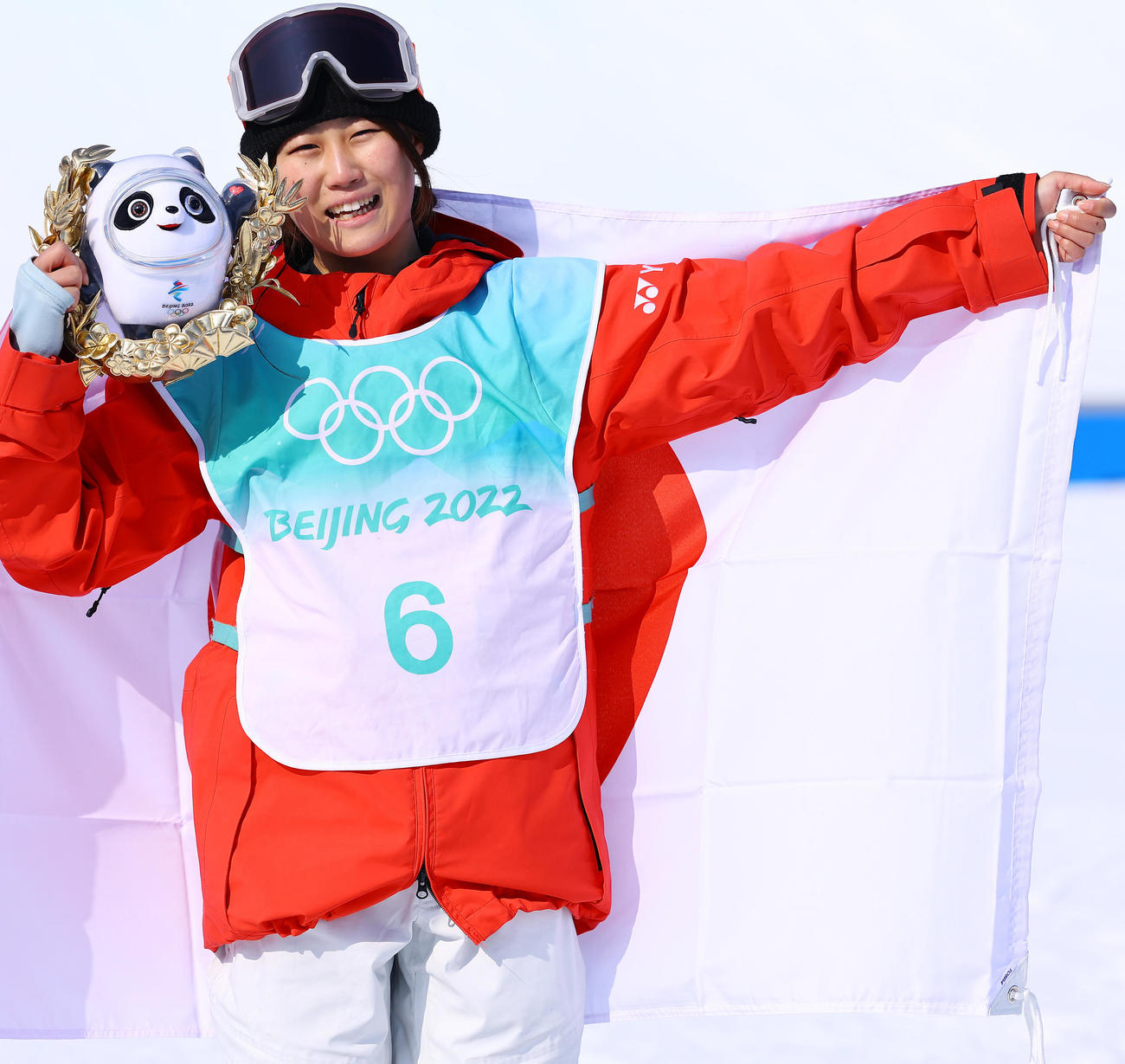 スノーボードビッグエアー女子で銅メダルに輝いた村瀬心椛は、日の丸を掲げ笑顔をみせる（撮影・垰建太）