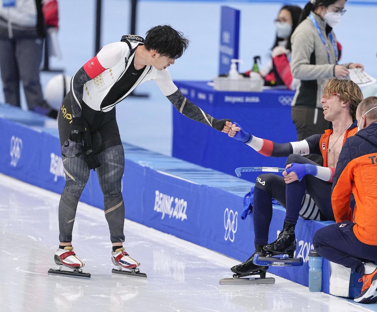 レースを終え、同走のオランダ選手（右）とタッチを交わす一戸誠太郎（共同）