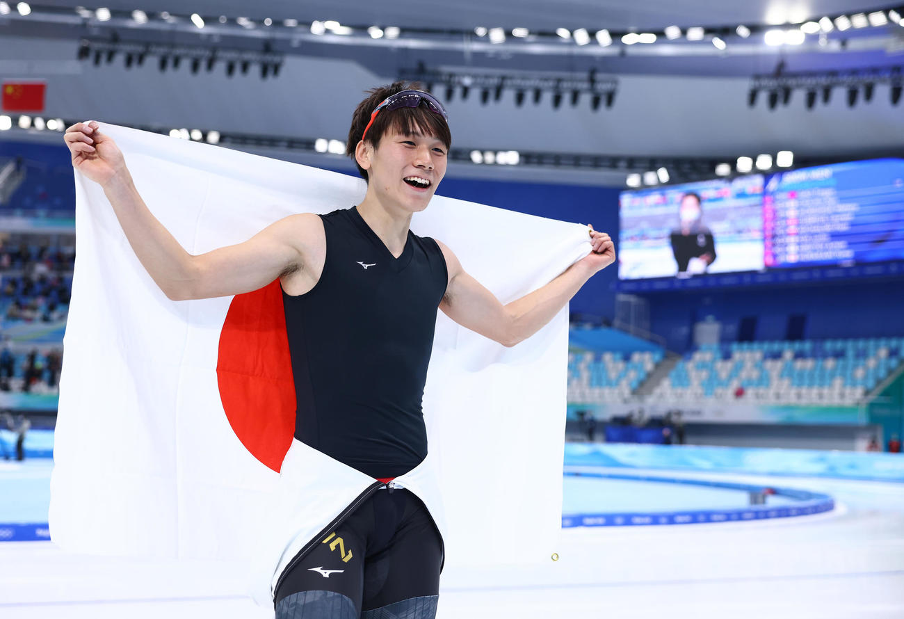 スピードスケート男子500メートルで銅メダルをに輝き笑顔で日の丸を掲げる森重（撮影・垰建太）