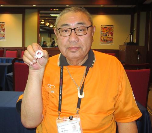 1964年東京五輪のボランティアバッチを手にする白井正一さん