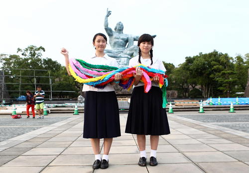 平和祈念像の前で千羽鶴を持つ高校生平和大使の山西咲和さん（左）と徳永雛子さん（撮影・三須一紀）