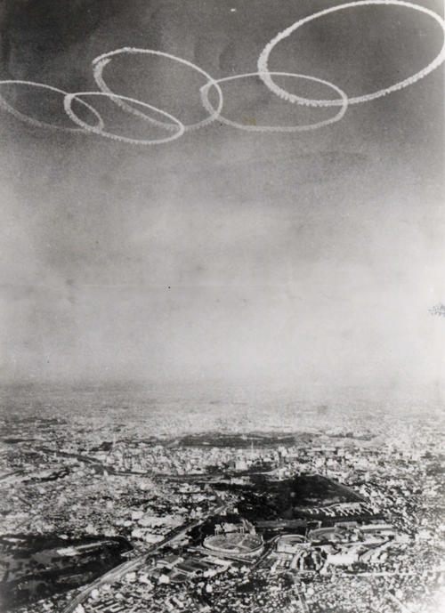 1964年東京五輪の開会式で、国立競技場の上空にブルーインパルスが描いた5つの輪（航空自衛隊提供）