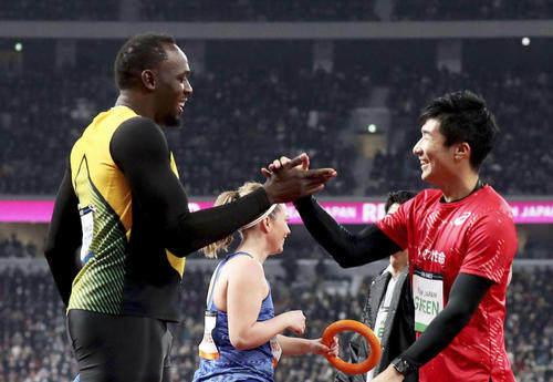 19年12月、国立競技場のオープニングイベントでリレーを走り終えた後、握手するウサイン・ボルト氏（左）と桐生（JSC提供・共同）