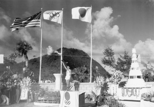 64年9月8日、東京五輪沖縄県聖火リレー初日の最終走者、徳村政勝さんが聖火宿泊地となった名護市嘉陽地区に到着(沖縄県名護市久志支部体育協会提供)