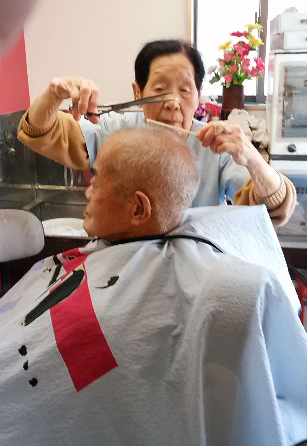 103歳の現役理容師としてお客さんを整髪する箱石シツイさん（家族提供）
