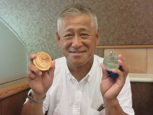 左手に88年ソウル五輪銀メダル、右手に92年バルセロナ五輪銅メダルを持ち、笑顔を見せる西正文氏