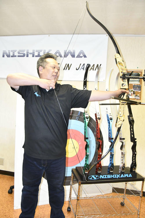 製作した「ハンドル」を装着したアーチェリー弓具を持つ西川社長