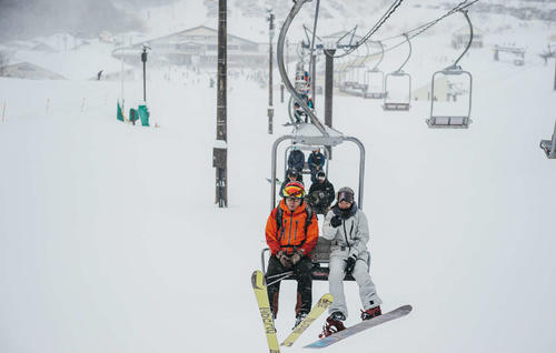 リフトに乗るスノーボード女子の鬼塚雅（右）と星野リゾートの星野佳路代表（星野リゾート提供）