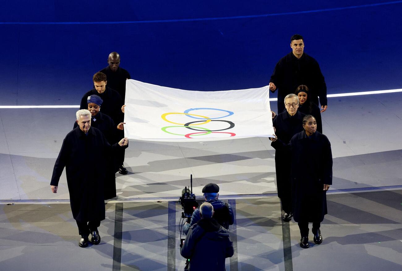 ミラノ・コルティナ五輪の開会式で五輪旗を運ぶ秋葉忠利前広島市長（右列2人目）、ピタ・タウファトファ（同4人目）、エリウド・キプチョゲ（左列4人目）ら（ロイター）