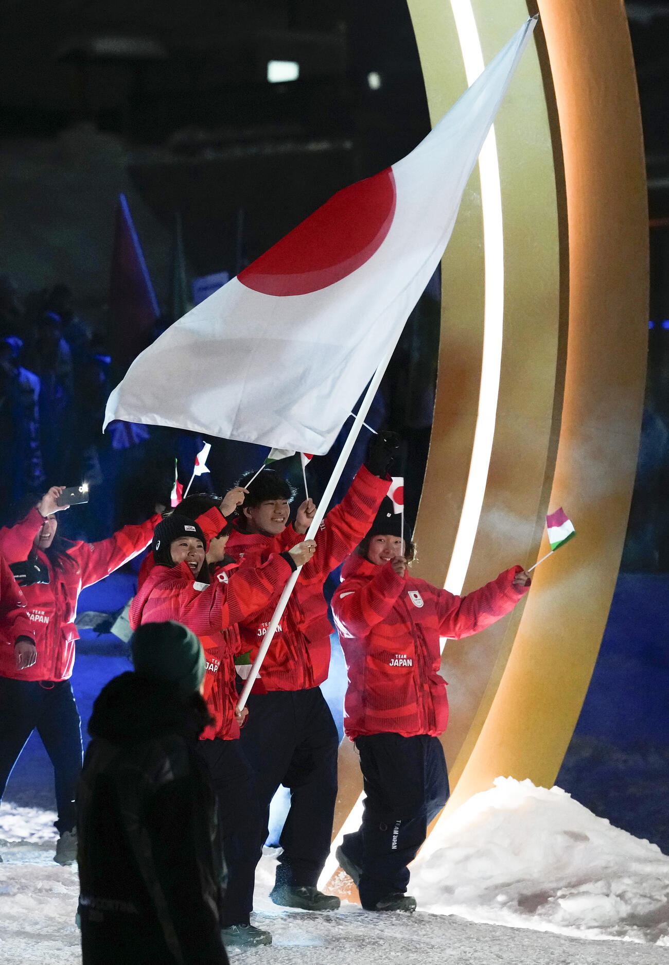 ミラノ・コルティナ冬季五輪の開会式で入場行進する、（右から）長谷川帝勝、木俣椋真、旗手の冨田せな（共同）