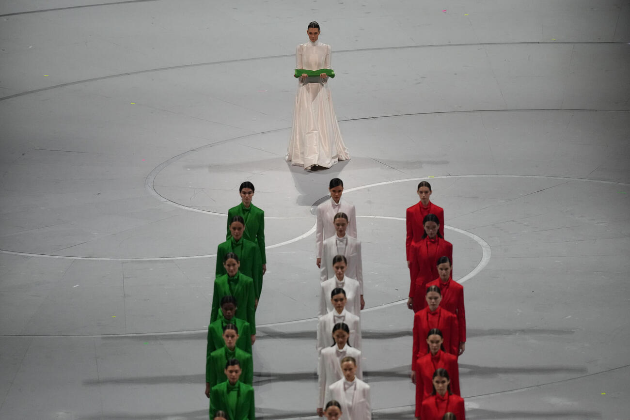 五輪開会式でイタリア国旗を運ぶビットリア・チェレッティさん（後方と）ジョルジオ・アルマーニさんが創作した衣装をまとう人たち（AP）