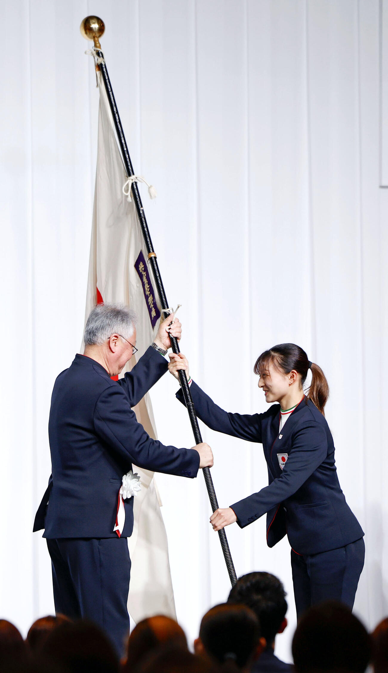 ミラノ・コルティナ冬季五輪の日本選手団解団式で伊東秀仁団長に団旗を手渡すフィギュアスケートの坂本花織（共同）