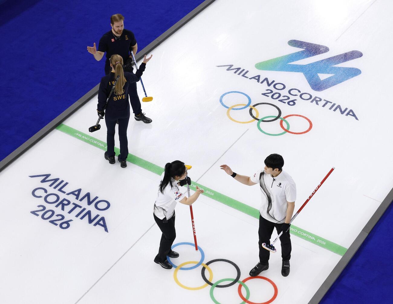 ミラノ・コルティナ冬季五輪の開会式に先立ってスタートしたカーリング混合ダブルスで、韓国組（右側）に勝利したスウェーデン組（共同）