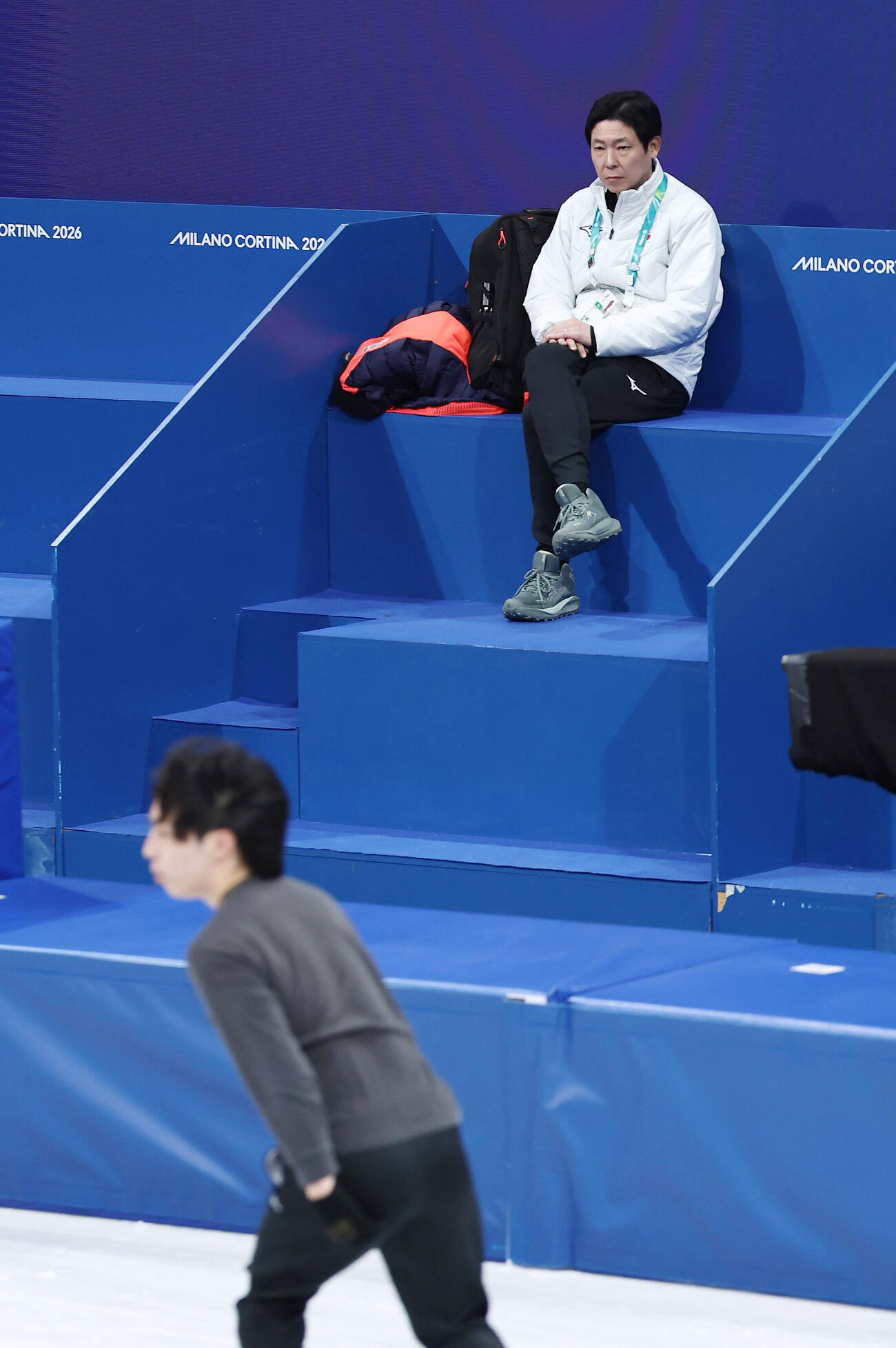 団体日本チームの応援席から鍵山優真と三浦佳生の公式練習を見守る日下コーチ（撮影・前田充）